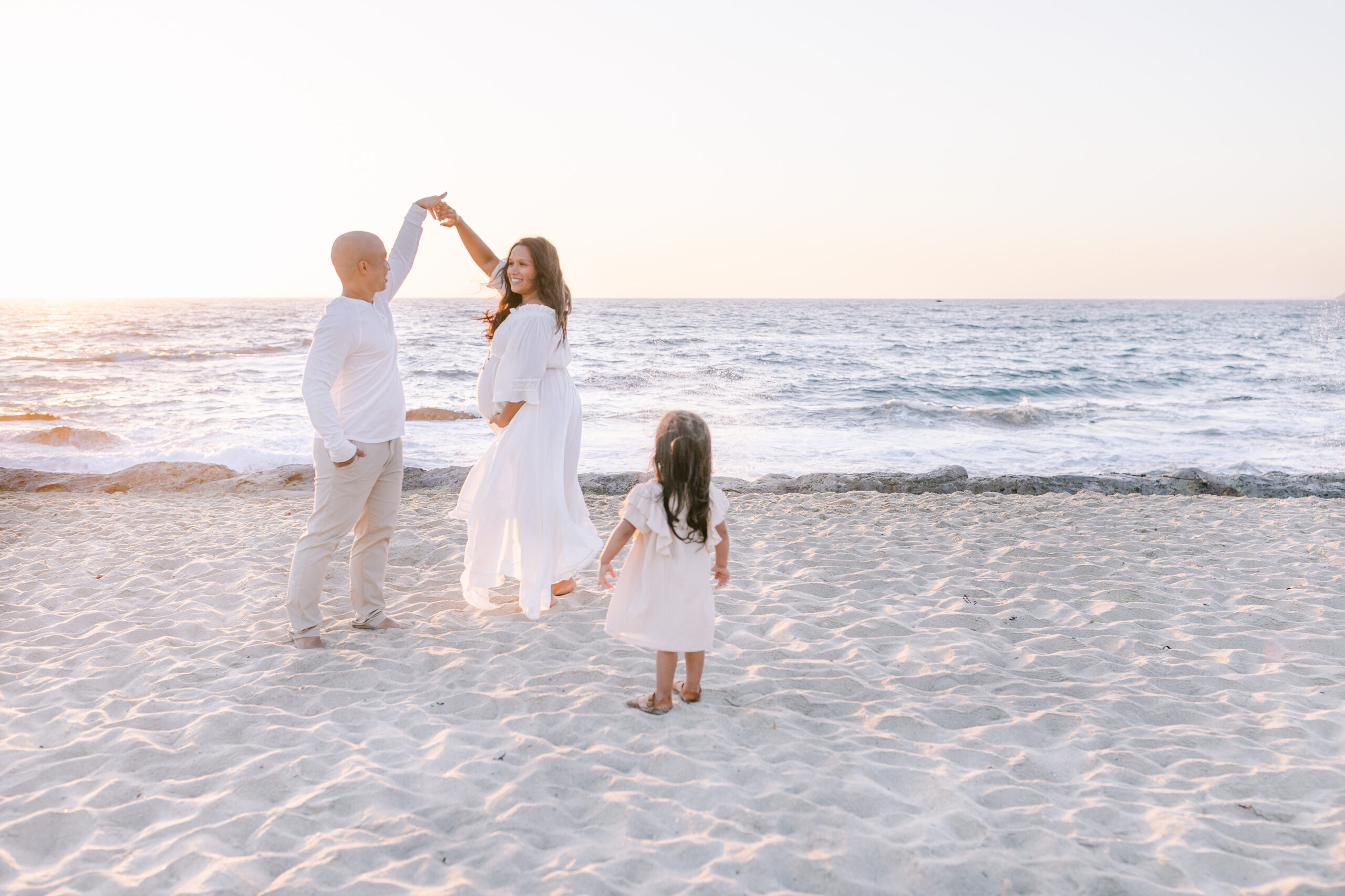 family dancing on beach during photographer session in orange county
