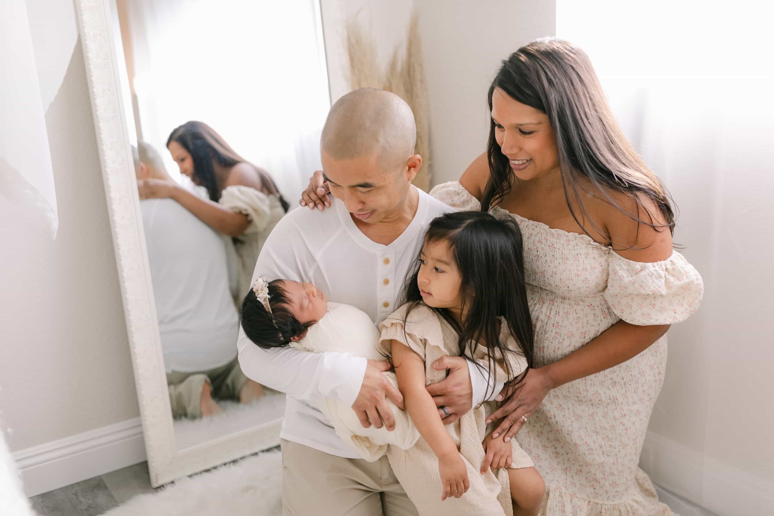 Family holding infant daughter and newborn baby capturing baby's first year milestones