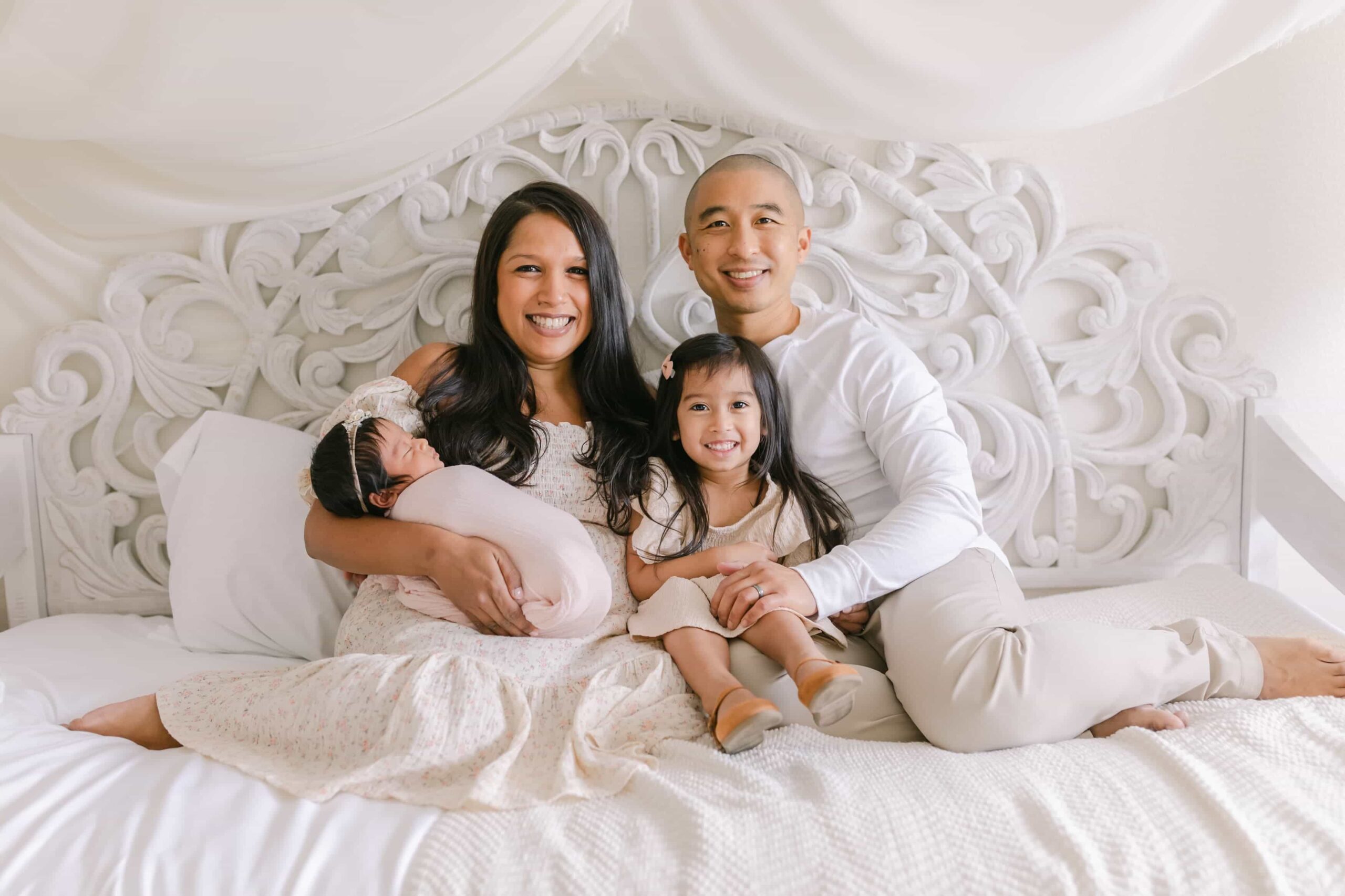 family on bed with daughter and newborn baby during photography session in orange county