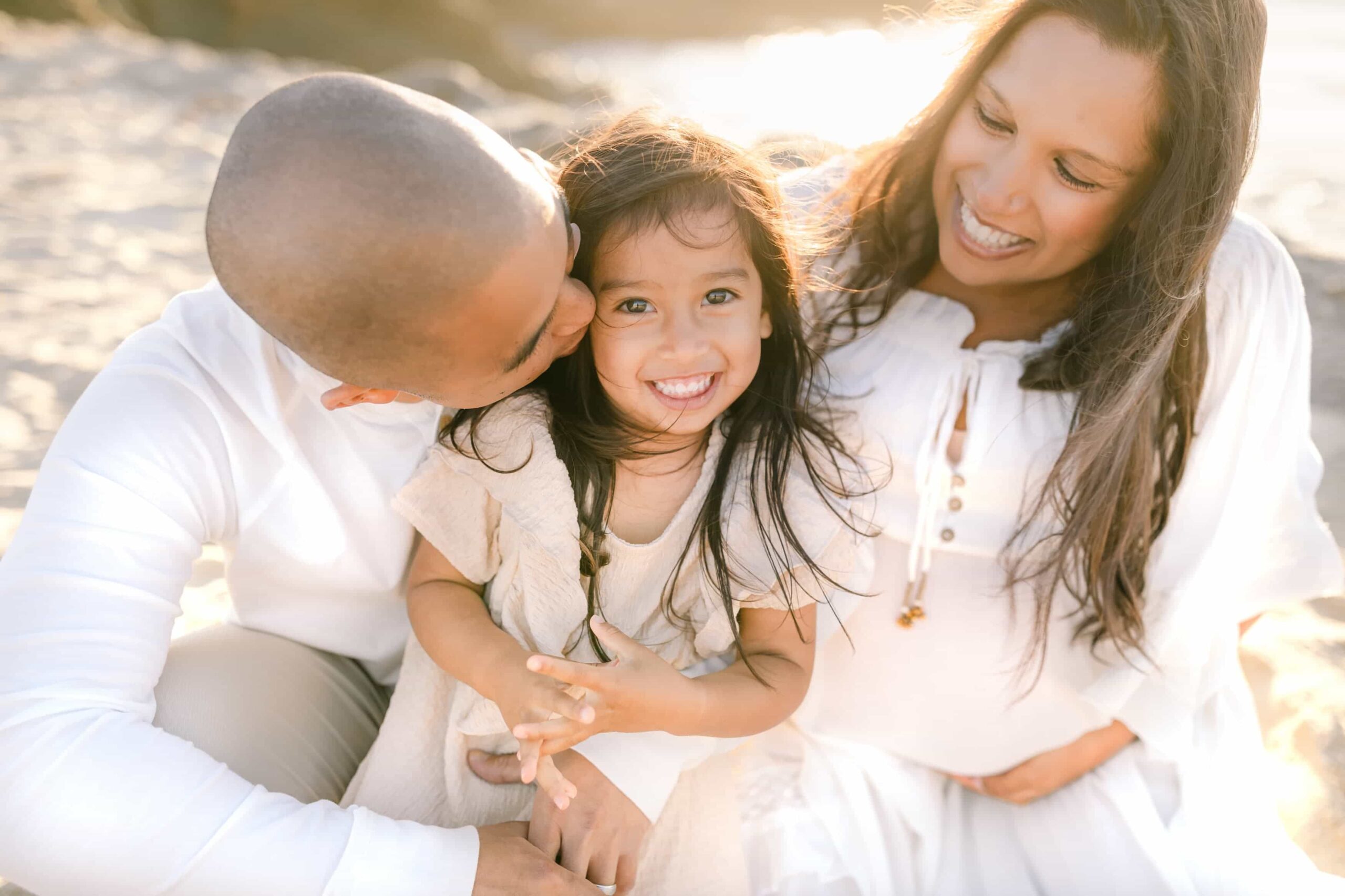 young daughter smiling while being held with family during photo shoot capturing milestones