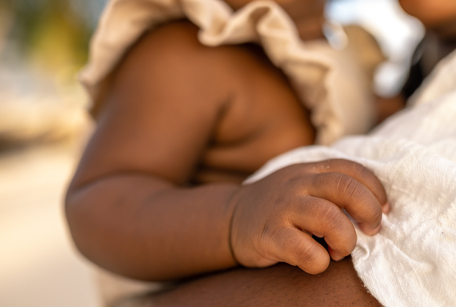 Details of a toddler's hand holding onto mom's dress