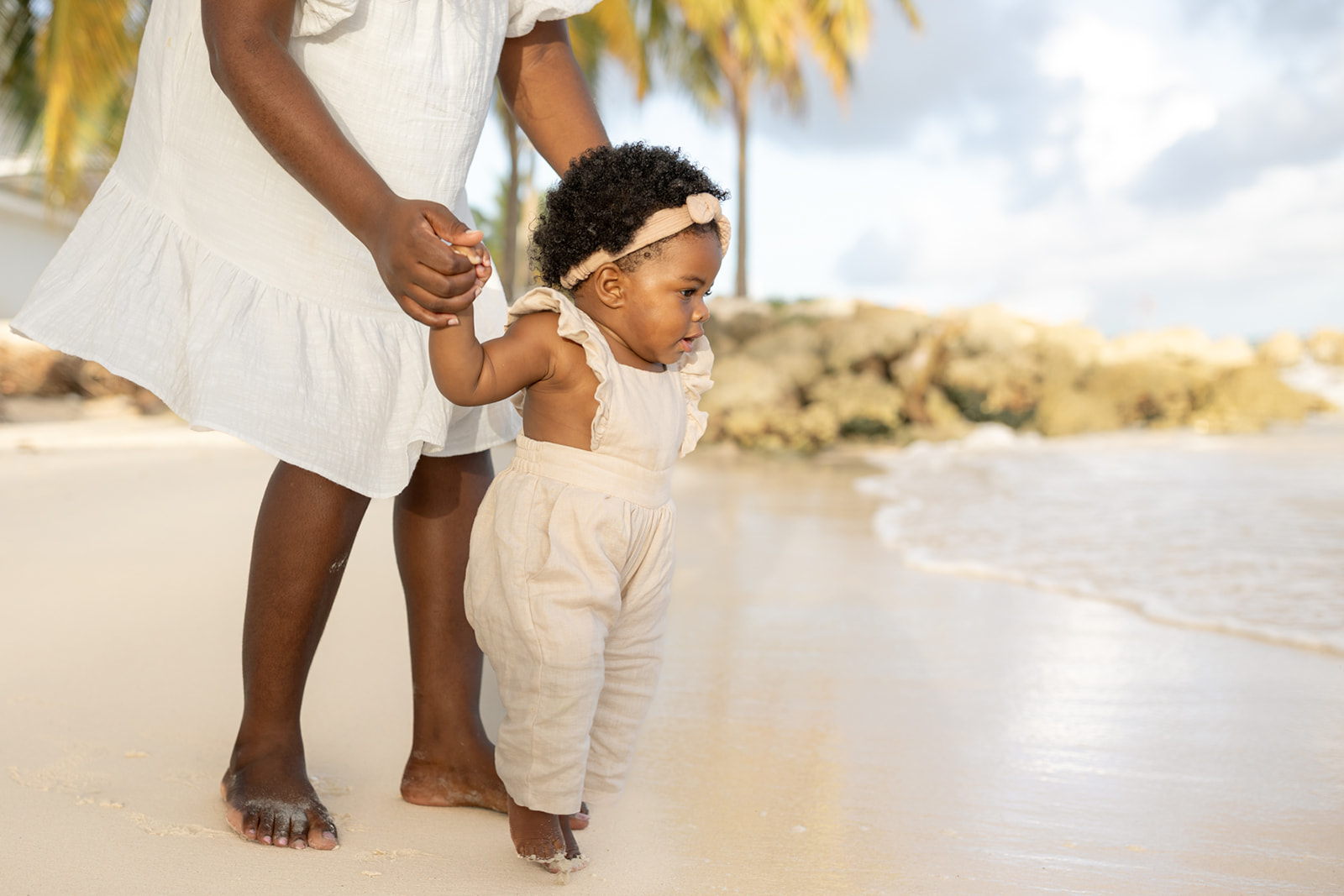 A mother leads her toddler daughter to the water on a beach before visiting an orange county Pediatrician