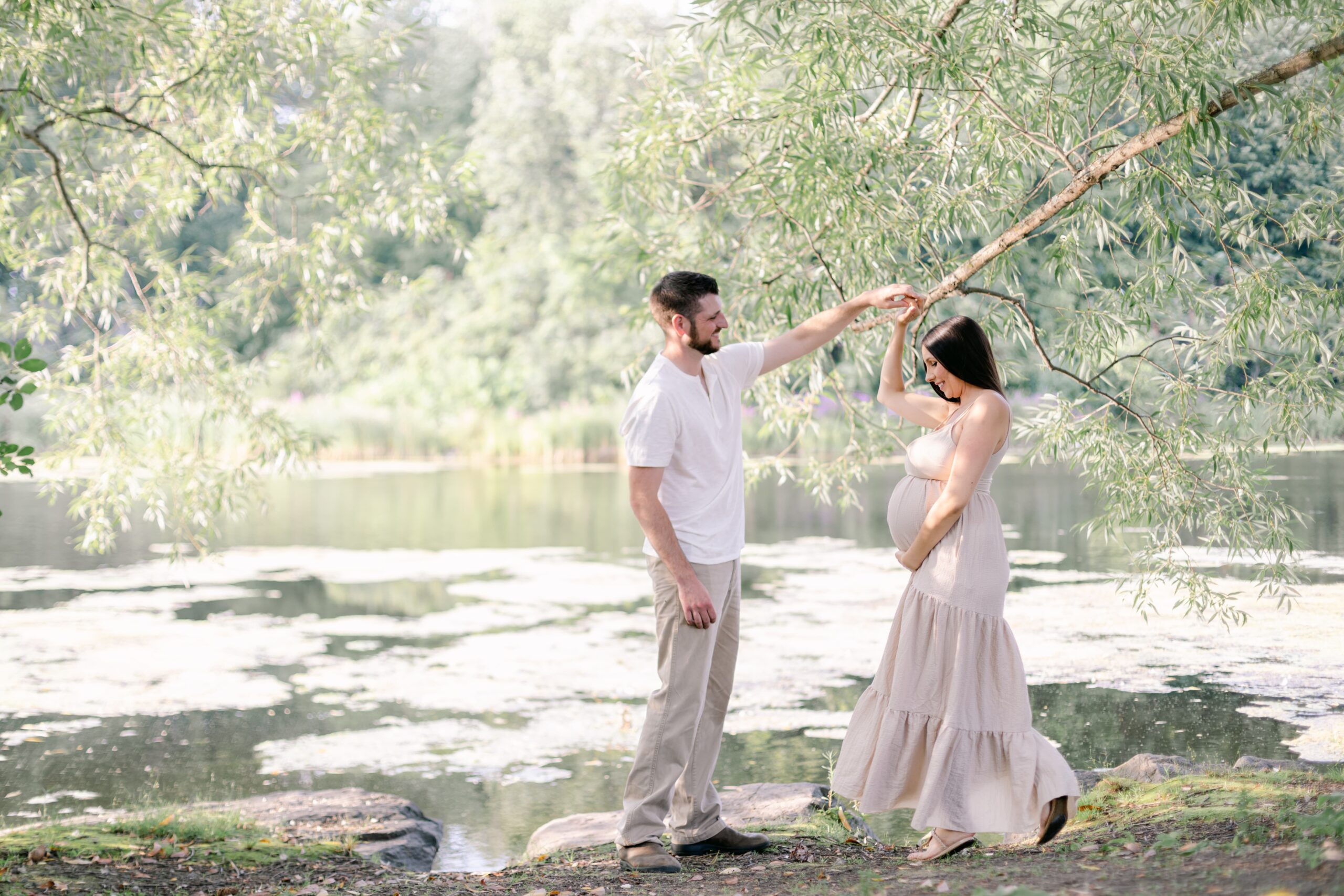 Expecting parents dance under a tree on a lake before some orange county prenatal yoga