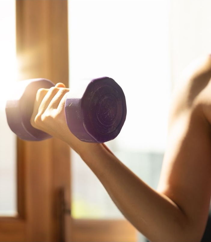 image of woman holding a dumbell in sunlight