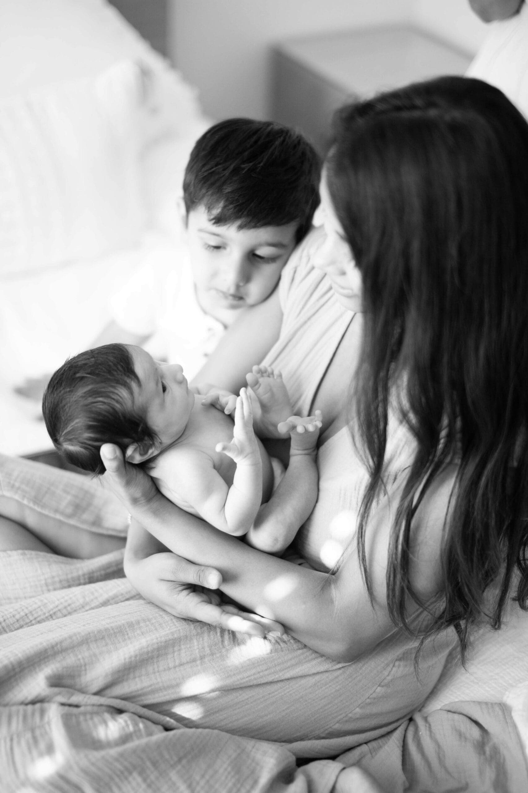 mom with newborn baby and toddler in a black and white image